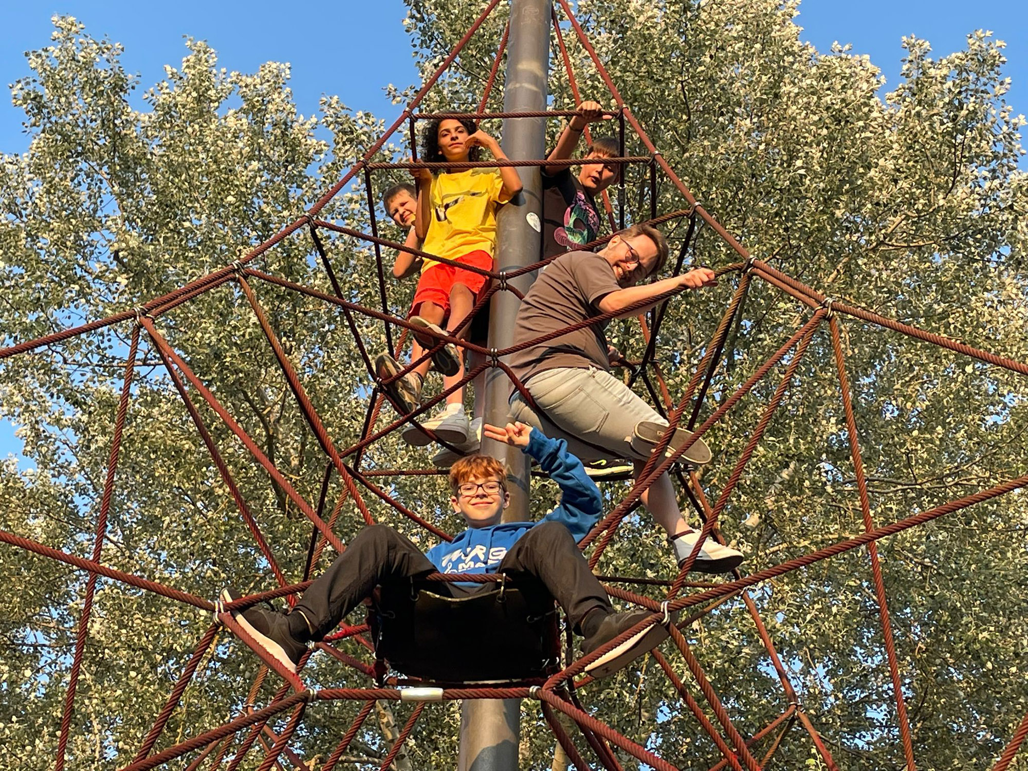 Kinder klettern auf einem Klettergerüst aus Seilen