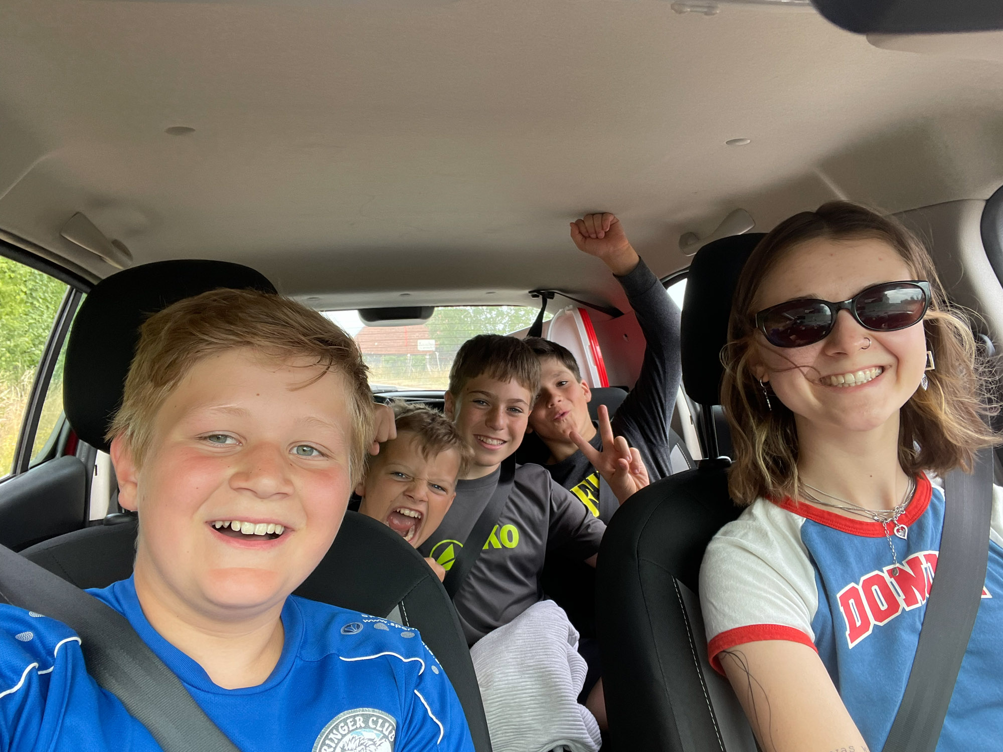 5 Kinder sitzen lachend in einem Auto