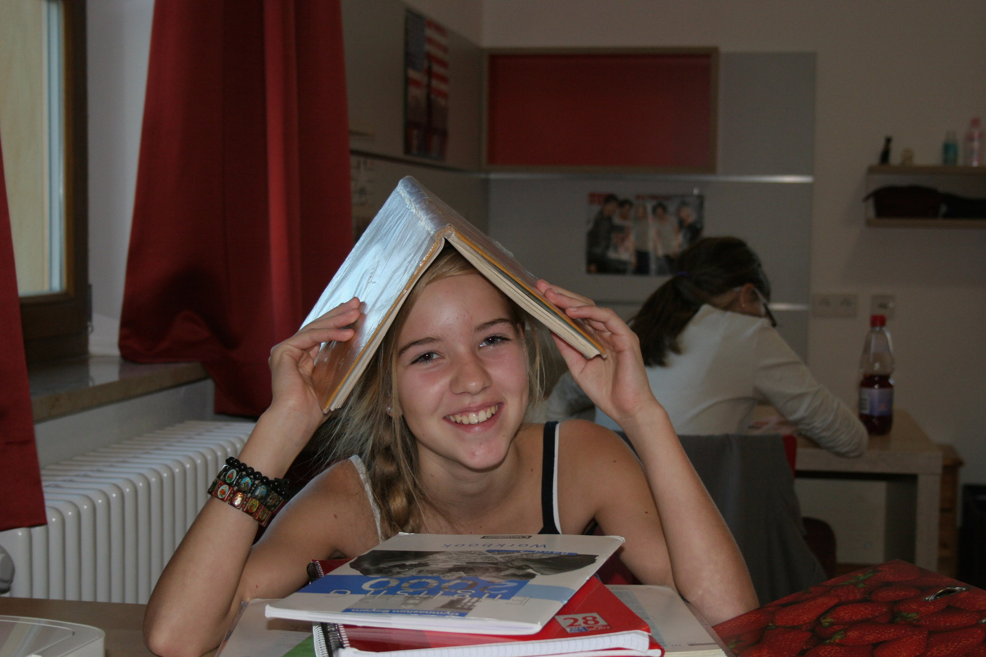 Lächelndes Mädchen hat ein Buch über den Kopf geklappt