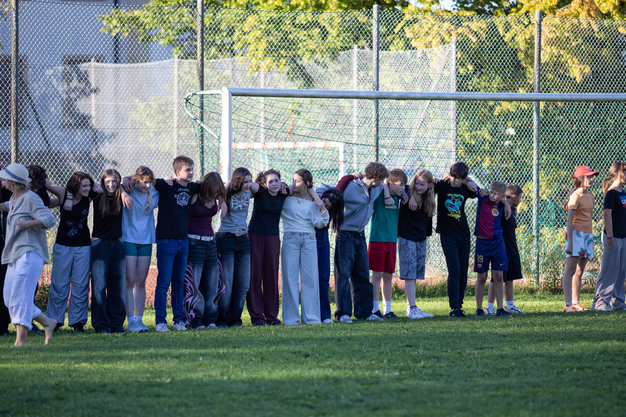 Viele Kinder stehen Arm in Arm auf einer Wiese vor einem Fussballtor